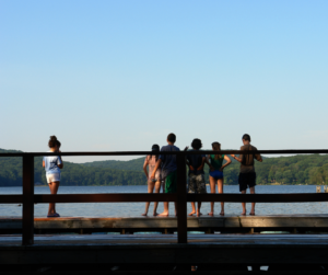 group of children looking into lake with a single child watching